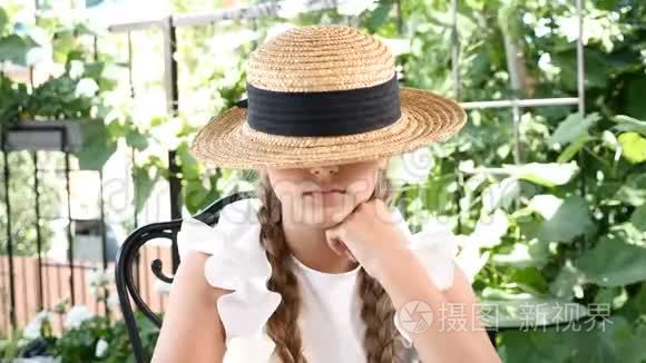 年轻迷人的微笑女孩玩草帽的肖像。 生活方式的概念。 快乐的童年。