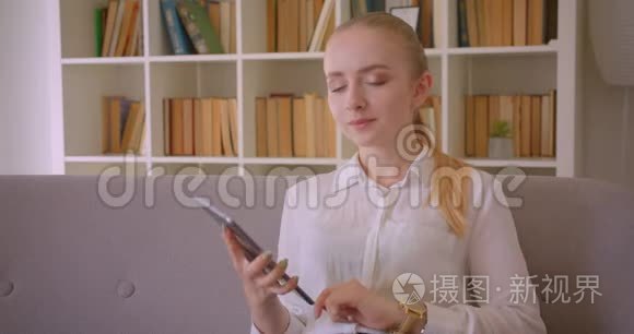年轻漂亮的白种人金发女学生使用平板电脑的特写肖像，并显示绿色的彩色屏幕。