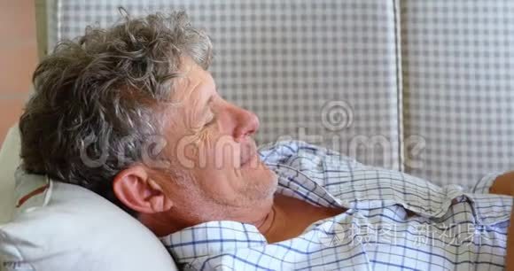 4k沙发上躺着数码平板电脑的老人