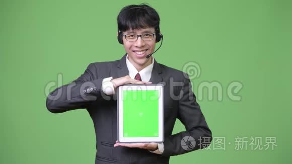年轻的亚洲商人，在呼叫中心的代表工作时，展示数码平板电脑的摄像头