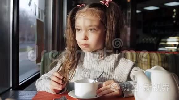 可爱的小女孩用糖果喝茶，坐在窗边，做着梦