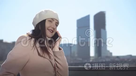 穿着外套带着电话的女人在一个大城市的高楼背景下