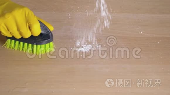 家庭主妇用橡皮手套用刷子用清洁粉擦拭脏桌子