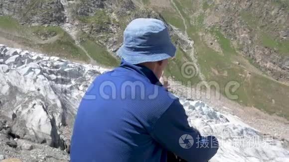 一个人坐在山上，从高处看冰川