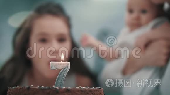 在家庭聚会上，女孩在生日蛋糕上吹蜡烛。 孩子生日快乐