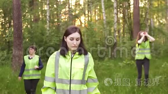 穿着绿色背心的志愿者穿过树林，寻找失踪人员