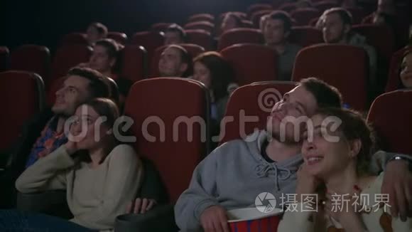 喜欢在电影院看电影的情侣。 吃爆米花的年轻人