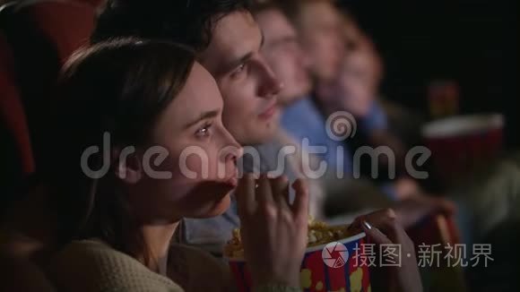 年轻夫妇吃一盒爆米花。 情侣看电影
