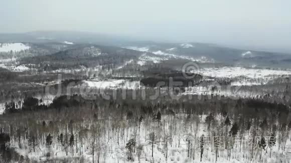 鸟瞰白雪皑皑的森林和山丘。 多云坏阴多雾天气.. 无人驾驶飞机飞行