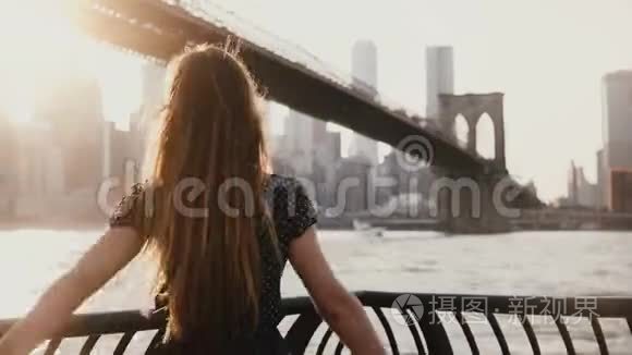 在纽约布鲁克林大桥附近，站在河堤旁的女孩被风吹过，手臂张开。