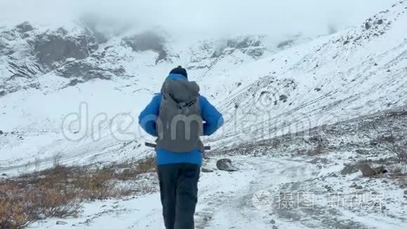 一位游客沿着白雪覆盖的小路散步。 一个人走在雪地里，在高山上远足。