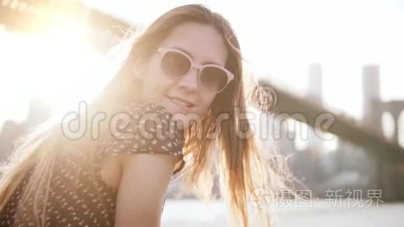 慢动作特写快乐的欧洲女游客戴太阳镜微笑相机日落纽约风景。