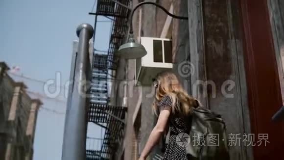 年轻女孩戴着太阳镜，背着背包走下红砖建筑的老楼梯，慢悠悠地走着。