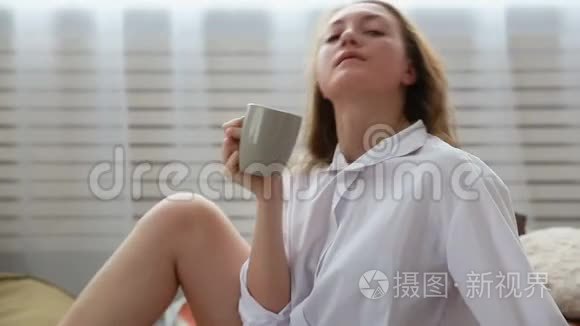 穿着白色衬衫`女人在床上喝咖啡