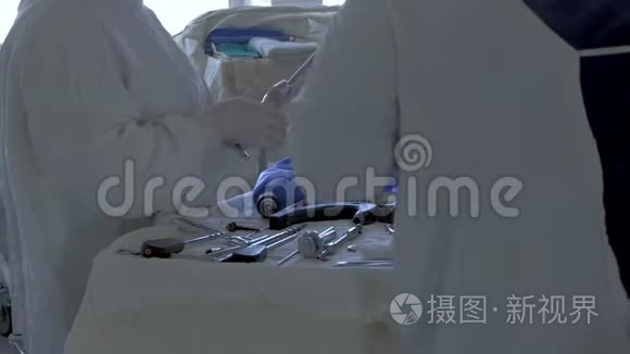 一组外科医生`医生为腿部手术选择特殊器械..