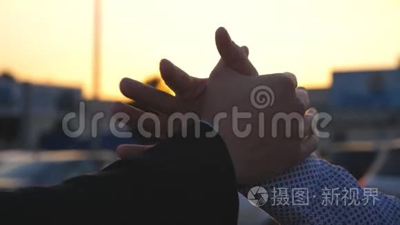 两位商务男士在户外与太阳耀斑握手。 男性手臂在外面晃动