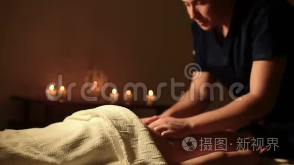 年轻的白人男性专业按摩师在黑暗的办公室里给一个女孩做水疗按摩。 中等距离