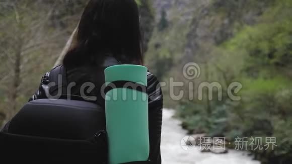 徒步旅行者女士背着背包在山上和山河湖上寻找，女孩在旅途中欣赏大自然的全景
