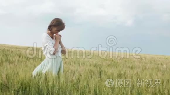 一个年轻的女孩在麦田里祈祷，一个女人在玉米穗中享受大自然，感谢上帝，一个宗教和节日的概念