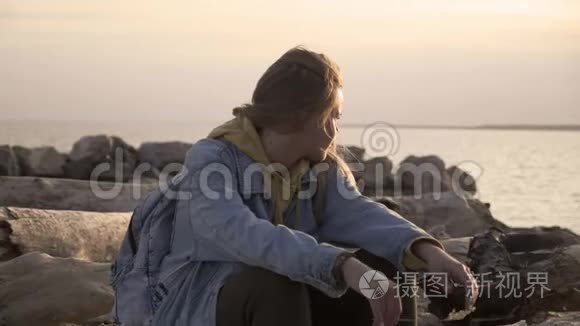 不高兴的女孩坐在海滩上看日落视频