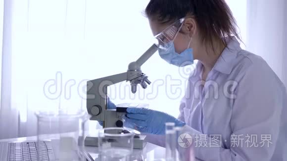 科学实验室，在无菌条件下用显微镜进行生物研究的妇女