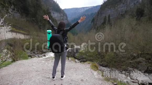 徒步旅行者女士背着背包在山上和山河湖上寻找，女孩在旅途中欣赏大自然的全景