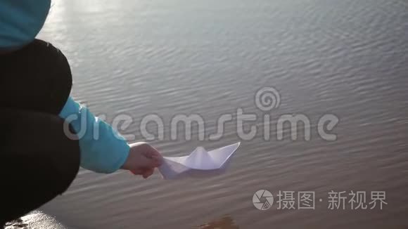 可爱的女孩在日落时在湖边玩纸船。 童梦和旅行理念，生活方式..