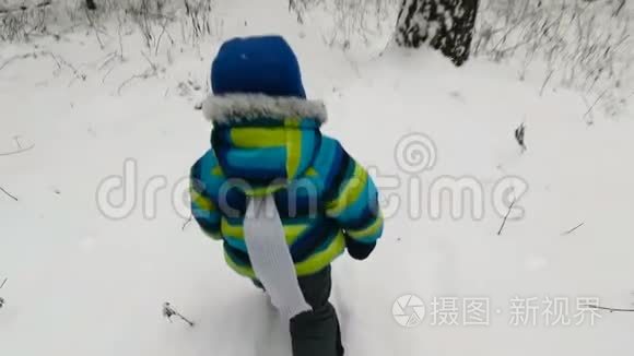 快乐的小男孩在冬天在公园里跑步。 快乐的男孩在雪地冬季公园玩得很开心。 微笑。 软焦