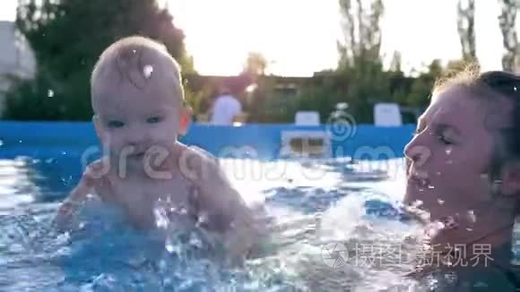 妈妈和孩子一起在游泳池里，快乐的小男孩在夏天炎热的日子里做着飞溅的水