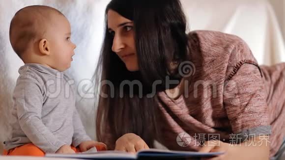 一位年轻快乐的母亲看着她的小儿子，微笑着。 一位有爱心的母亲给她的孩子读童话故事