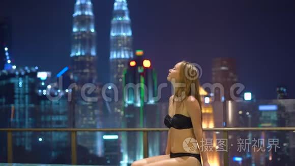 美丽的年轻女子在屋顶的游泳池里玩得很开心，可以看到摩天大楼。 亚洲概念旅行