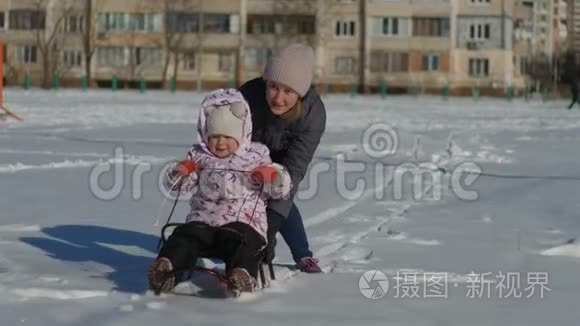 妈妈把一个小女儿卷在雪里雪橇上