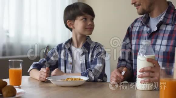 父亲用玉米片倒牛奶，儿子和爸爸吃早餐