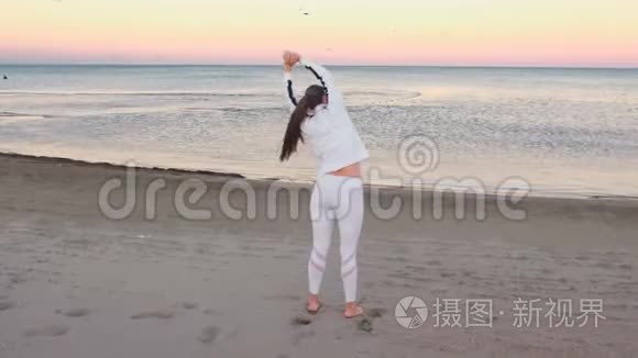 年轻女子正在做运动，以恢复呼吸在沙滩上日出在秋天。