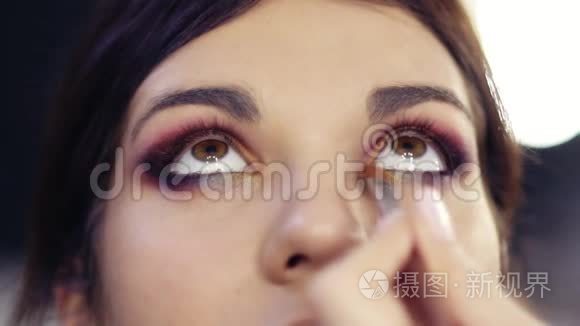 在美丽的黑发女孩的眼睛内角添加一些金色`眼影。 创造完美的色彩