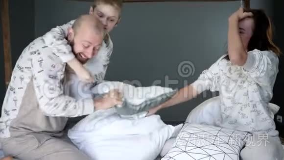 睡衣派对，儿子和父母穿着相同的睡衣，在床上用枕头打对方