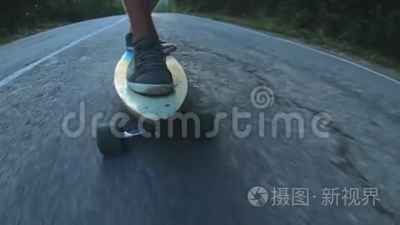 特写滑板少年骑户外.. 一个年轻人骑着长板在高速公路上。 森林里的米斯蒂路