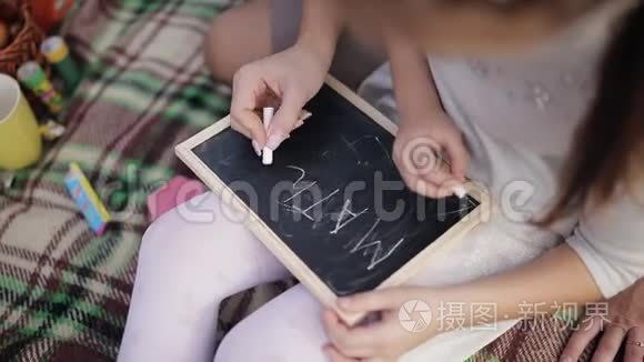 一个小女孩学会用粉笔在黑板上写字。妈妈教女儿写字母、字母表