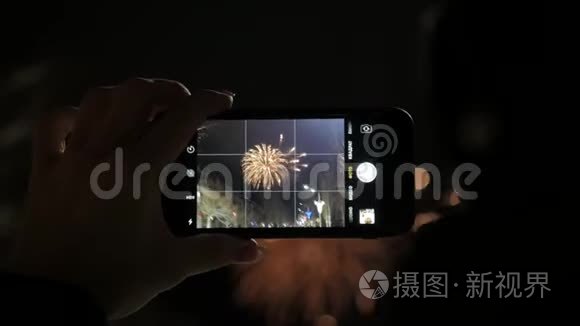 一个女人在智能手机上燃放烟花。 用智能手机制作美丽烟花的视频，供庆祝。