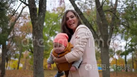 妈妈和孩子一起在秋天的公园玩耍，一家人在背景树上玩得很开心
