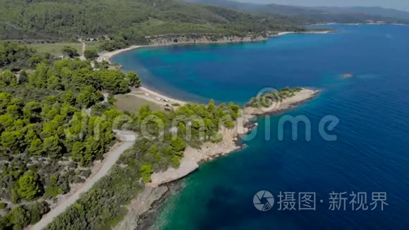 空中观看蓝色海面环绕树木。 深蓝色海洋水面海岸森林汽车道路的俯视图