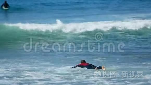 男子尝试在冲浪板上游泳，通过海浪在海洋，夏季积极运动