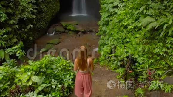 印度尼西亚巴厘岛丛林里一位年轻女子参观莱克莱克瀑布的空中镜头