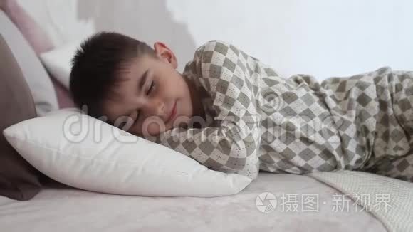 穿着睡衣躺在床上睡着的小男孩