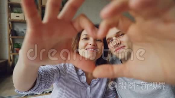 慢镜头描绘幸福的多民族夫妇用手做心，看着相机，微笑。 浪漫浪漫