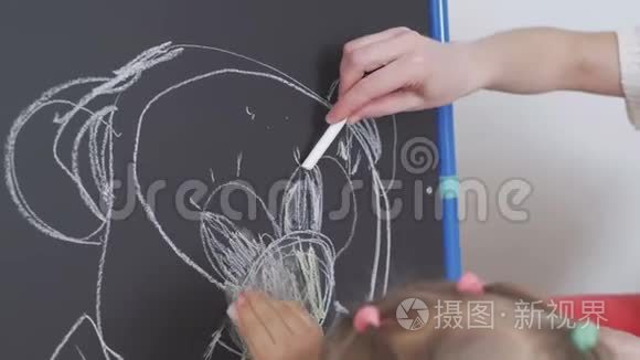 妈妈教小女孩用粉笔在黑板上画画。