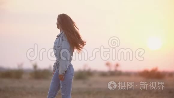 穿牛仔裤的女孩在夕阳的天空中视频