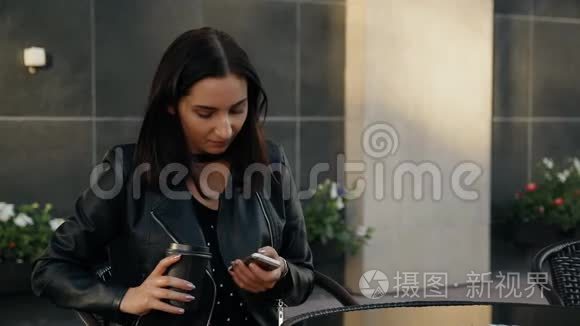 一个年轻的女人坐在咖啡馆里使用智能手机。