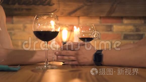 浪漫的一对夫妇手拿蜡烛和酒杯在桌子上。 男人和女人牵手浪漫的约会