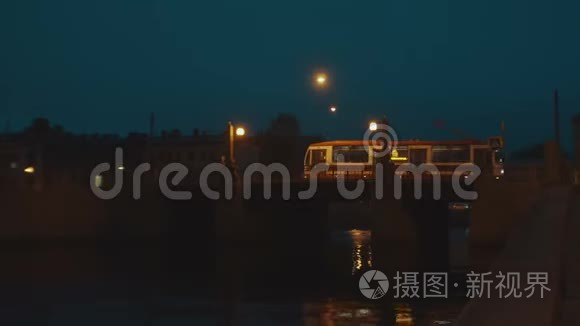 城市有轨电车夜间在旧城的桥上行驶。 桥上的灯是黄色的。